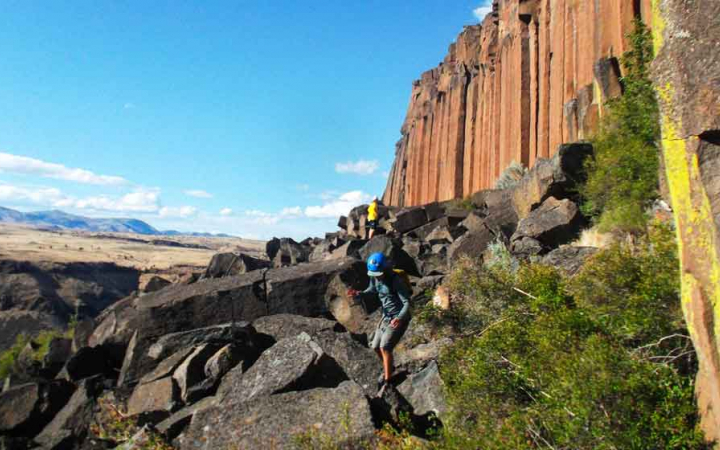 a person wearing a helmet navigates large rocks on an outward bound course